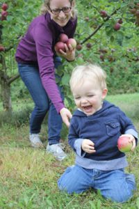 Adoptive mom and her toddler son picking apples