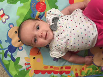 Smiling baby girl laying on a play mat