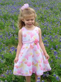 Blond little girl in a dress standing in a field of flowers
