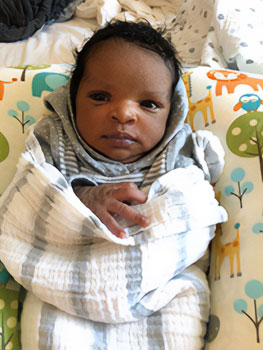 Lifetime baby Miriam loosely swaddled, resting on a pillow