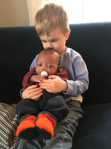 big brother holding baby on lap