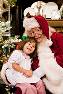 Smiling little girl posed on Santa's lap