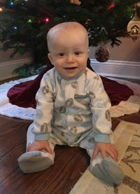 Adopted boy with football pajamas under Christmas tree