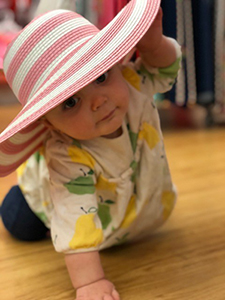 Baby girl crawling and wearing a large hat