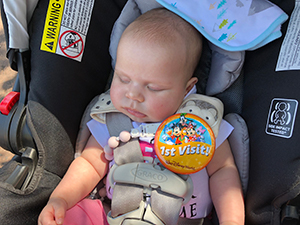 Adopted baby with sticker for first visit to Disneyland