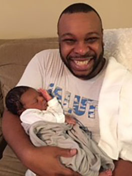 proud uncle holds his newly adopted nephew and smiles for the camera