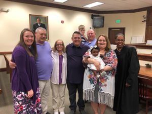 An adoptive family in the courtroom with the judge after their adoption finalization day