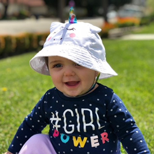 baby in a girl power shirt and hat smiles at camera