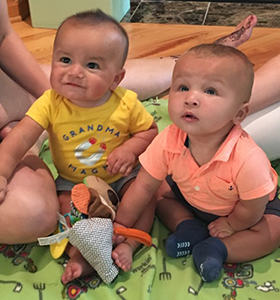 Newly adopted twins sitting on blanket look up at camera
