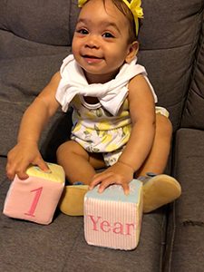 Baby girl holding blocks that read 1 year