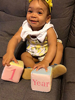 Baby girl holding blocks that read 1 year