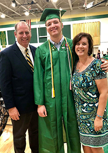 Adoptive parents pose with their son at his high school graduation