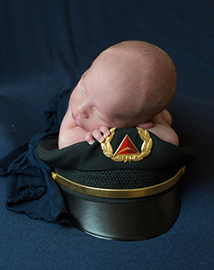 tiny baby sleeping on uniform cap