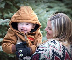 Mom in sweater holds child in hooded jacket