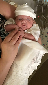 Newborn baby girl in a white hat and outfit
