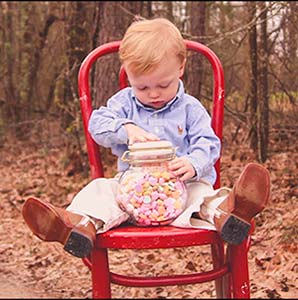 toddler on red chair with Valentine candy in jar