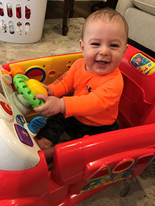 Giggling baby boy playing in a toy car