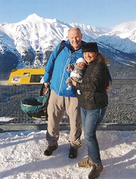 Alaskan couple in front of mountain with baby