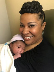 Happy black adoptive mom with her newborn baby on her chest