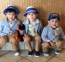 Three little boys in blue hats seated