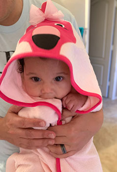 Baby girl wearing a hooded flamingo towel after bath