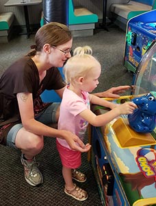 Adoptive mom playing with child at arcade