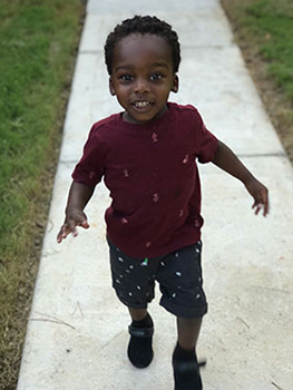 20-month-old toddler walking down the sidewalk