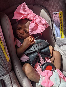 baby dressed in pink snuggles in her car seat