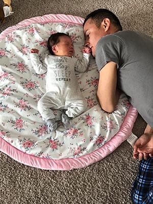 Dad snuggles on blanket with his sleeping adopted sweet baby girl