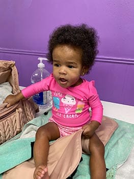 cute black baby girl sitting in pink outfit ready to play