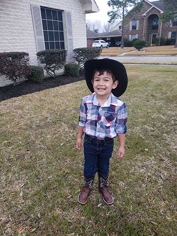 our son smiles at camera with his cowboy hat on
