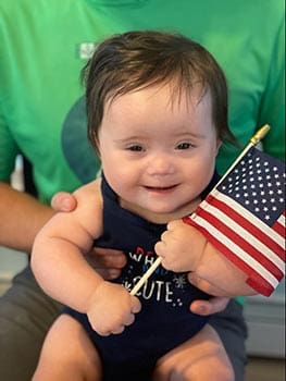happy baby hold flag and smiles at camera