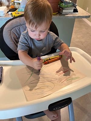 coloring in his high chair at already two