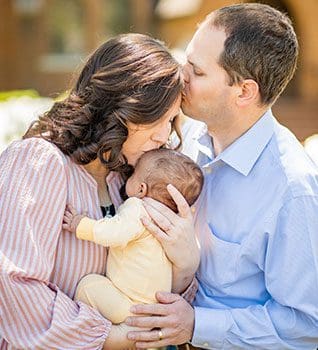 parents kiss newly adopted baby