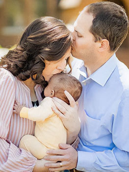 parents kiss newly adopted baby