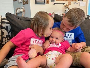 children giving kisses to their new sister