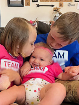 children giving kisses to their new sister