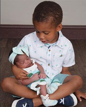 Big brother holds his newly adopted sister