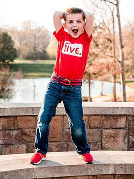 5 year old boy happily posing for camera