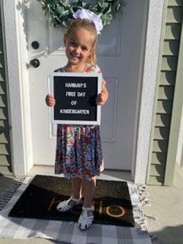 young girl starting Kindergarten and holding up a sign.
