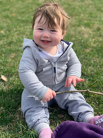 baby Luke smiling at camera while sitting on the lawn