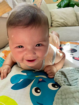 baby learning to crawl smiles at the camera