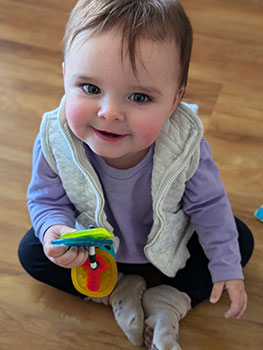 baby sitting on floor smiling at the camera